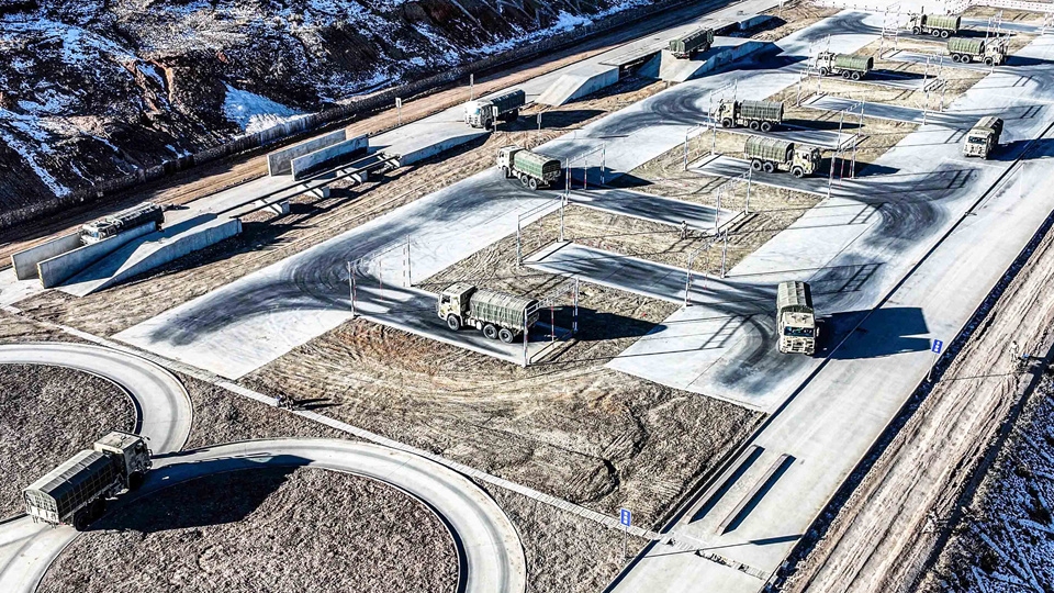 Military trucks maneuver on training ground