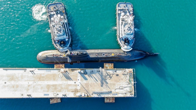 Tugboats help submarine dock at port