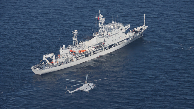 Naval ship and air force helicopter in joint search and rescue training