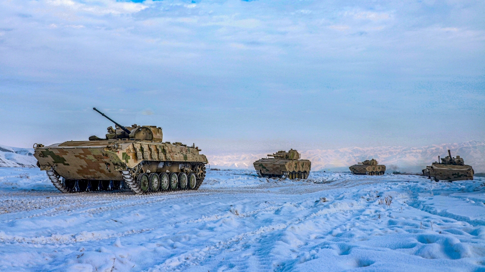 Armored vehicles march on snow field